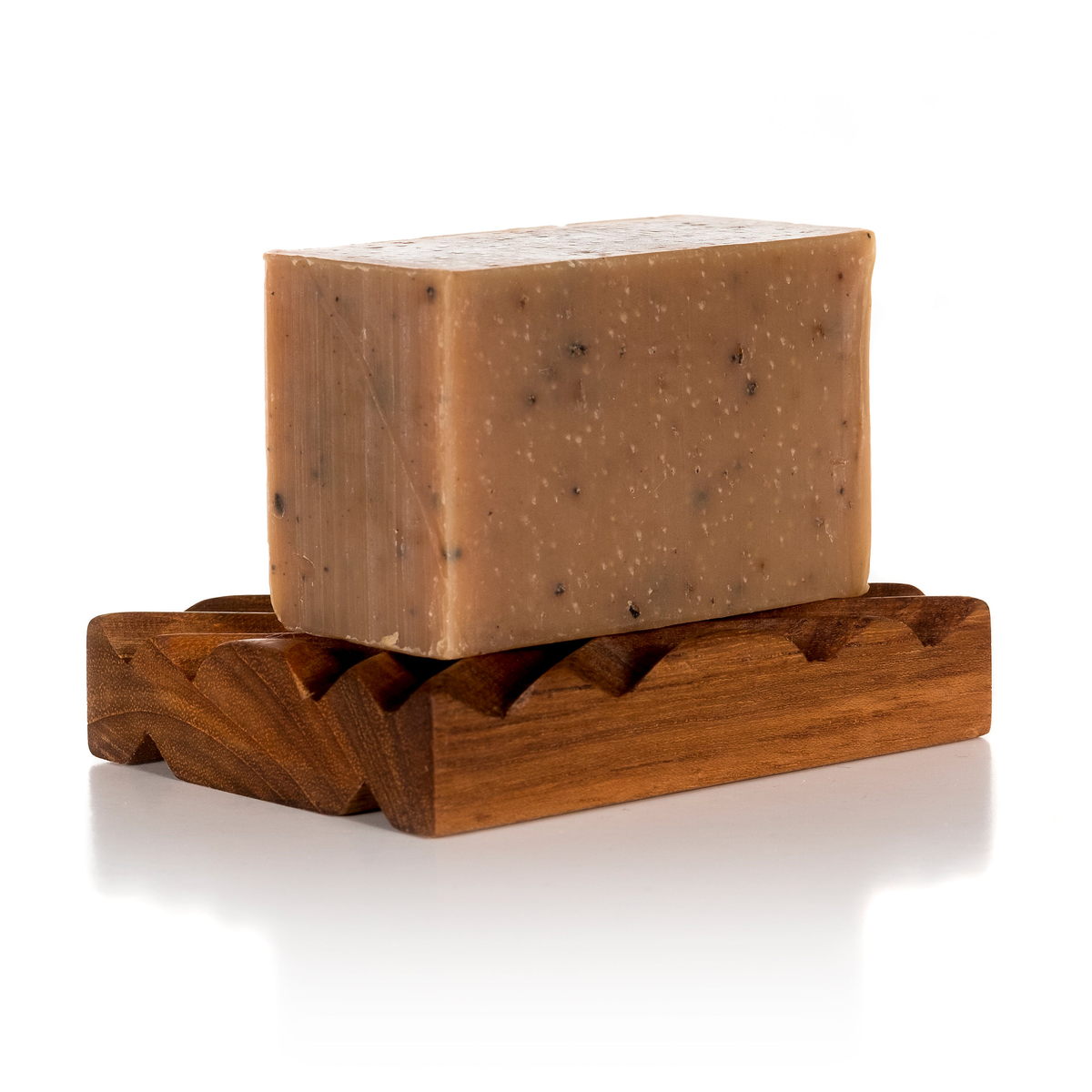 Unwrapped goat milk soap bar on a teak soap dish